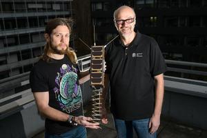 © Oliver Dietze/ Gilles Nies und Professor Holger Hermanns mit dem Nachbau eines Nano-Satelliten, dessen Leistungsfähigkeit nun mit ihrer Hilfe garantiert werden kann