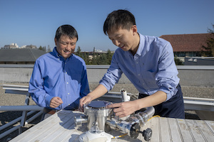 © L.A. Cicero / Professor Shanhui Fan und Postdoktorand Wei Li auf dem Packard Electrical Engineering-Gebäude mit dem Gerät, das die Wirksamkeit eines zweischichtigen Solarmoduls beweist.